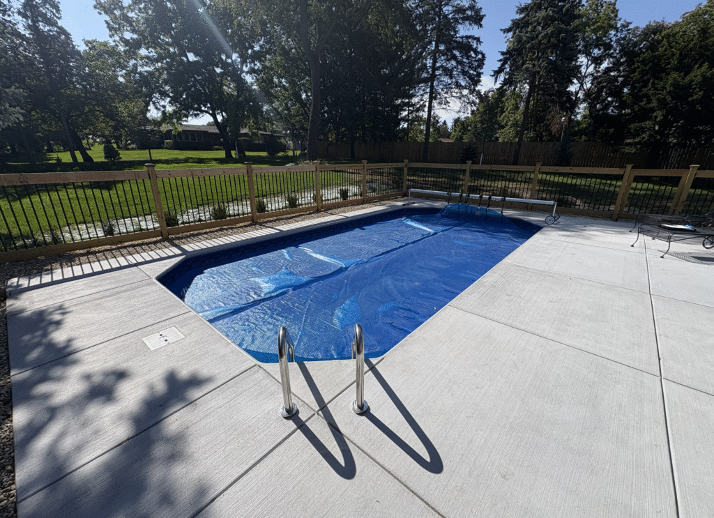 Aerial view of a rectangular inground swimming pool set within an open lawn and landscaped residential backyard.